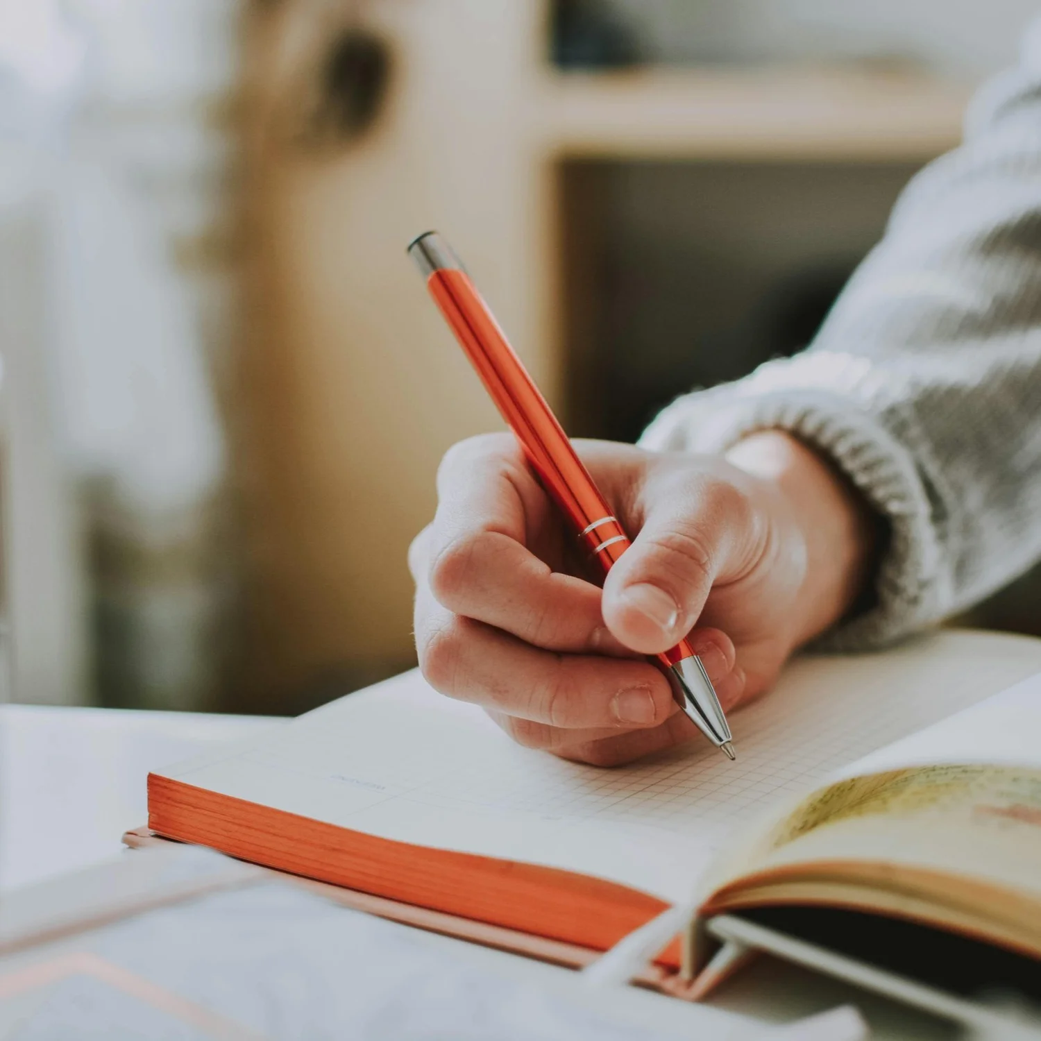 A person writes in a journal using a pen