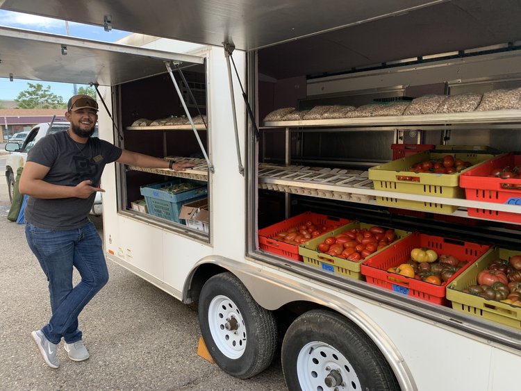Man smiling next to a mobile vegetable stand