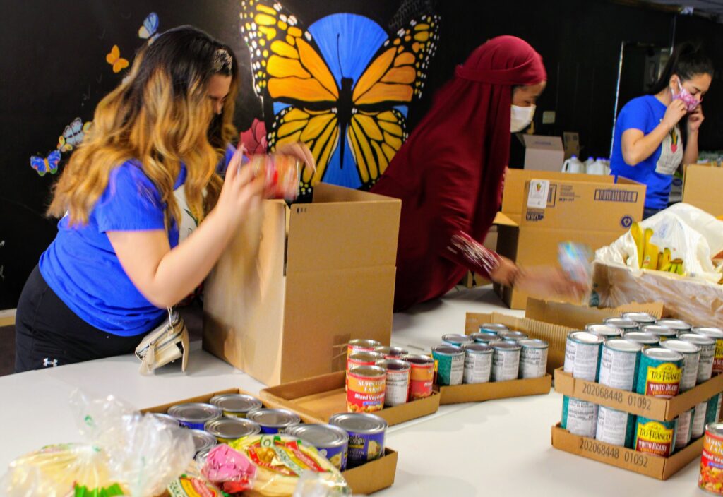 Volunteers packing cans of food into cardboard boxes