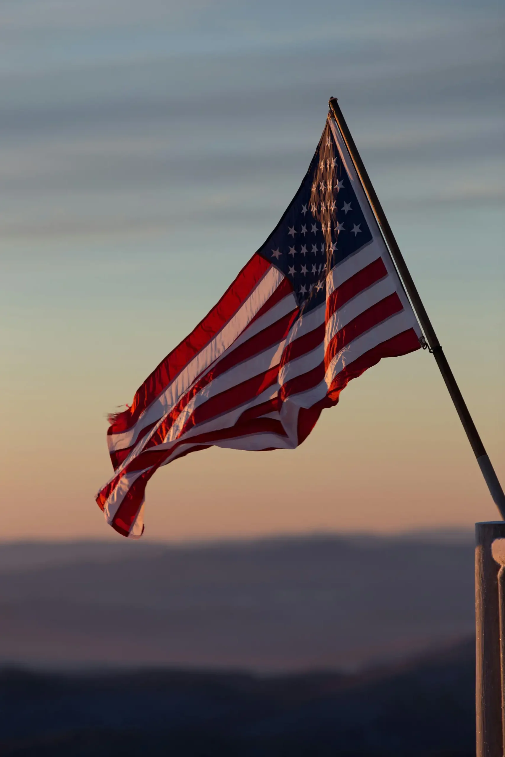 The American flag waving in the sky during sunset